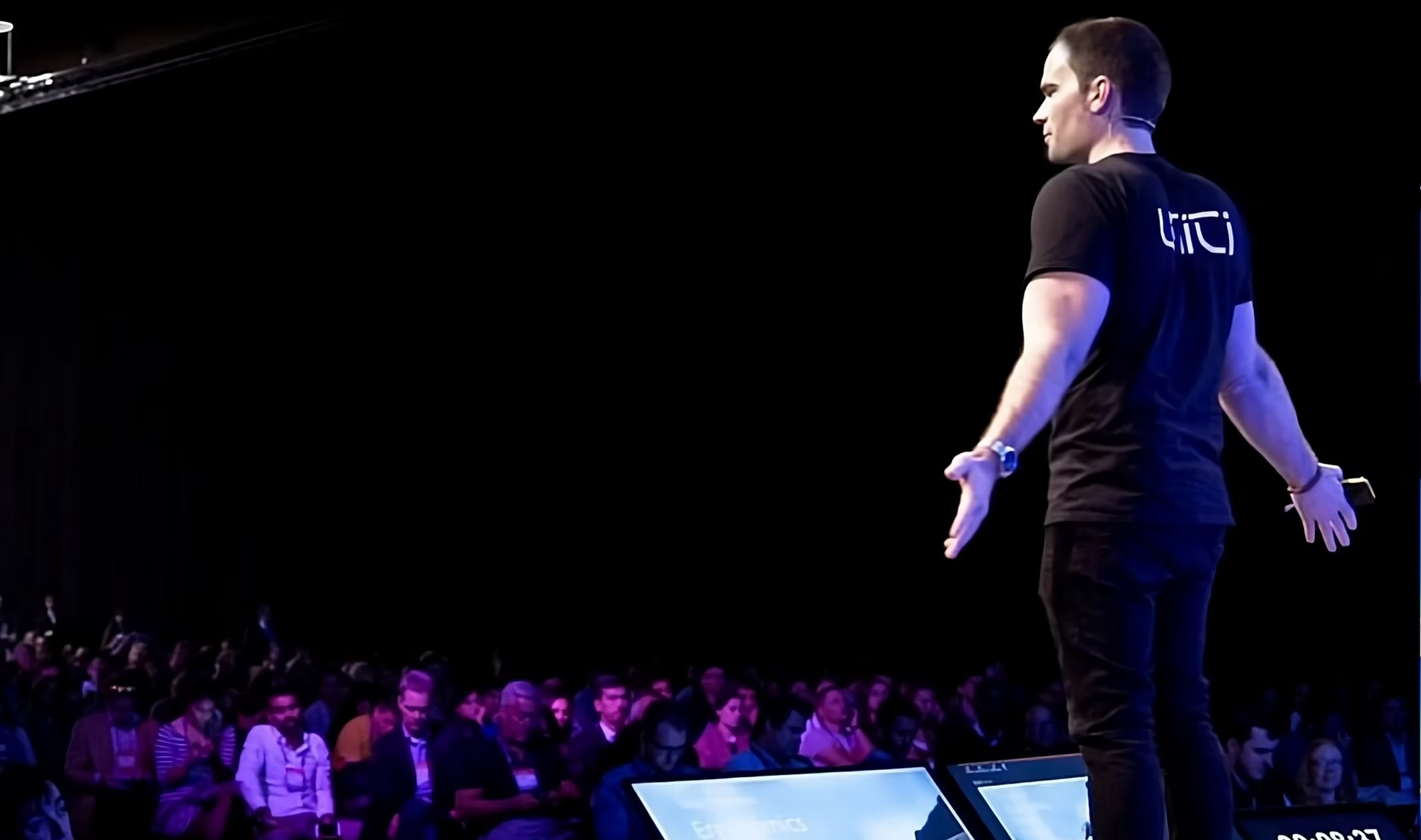 Lewis Horne at Web Summit in his Uniti shirt, arms out to the audience