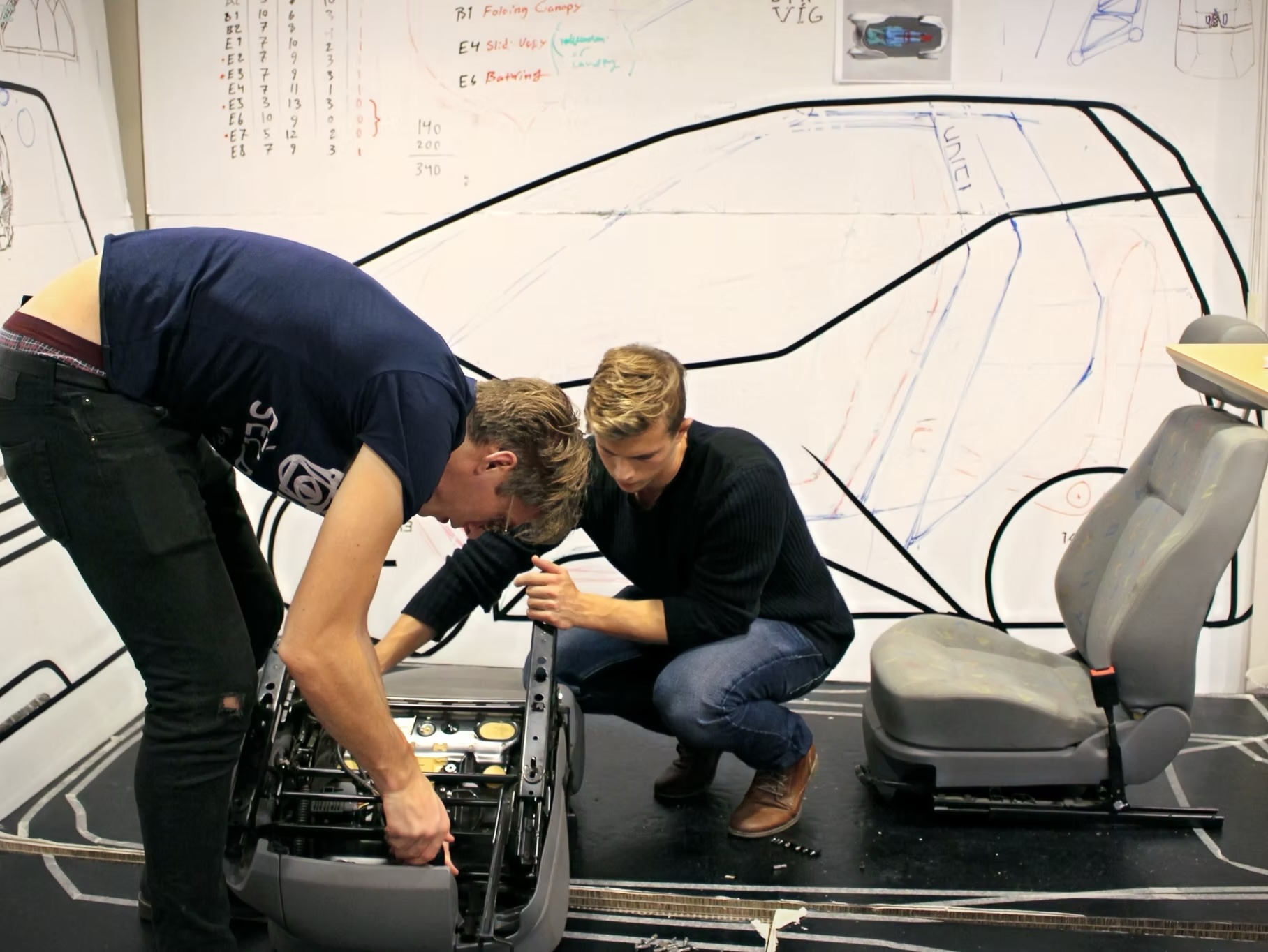 The Uniti team building a full-size vehicle model beneath a hand-drawn outline at Lund University